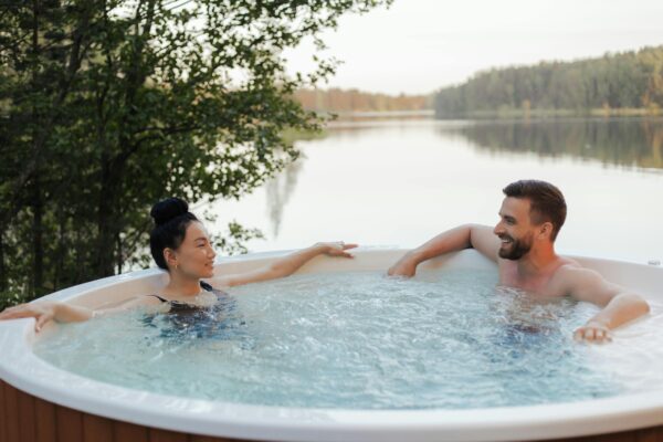 A couple relaxing in a hot tub, surrounded by steam, enjoying a romantic moment together.