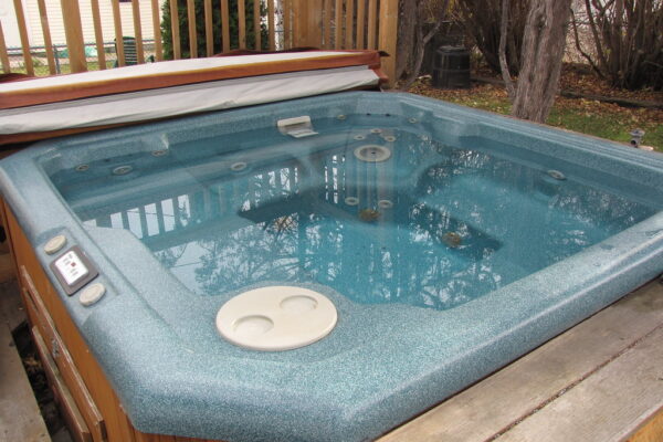 Outdoor hot tub with a wooden surround and a reflective blue interior, situated on a wooden deck