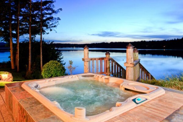 A peaceful hot tub on a wooden platform, offering a scenic lake view